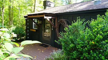 A cabin with a wooden deck, a door, and a chimney.