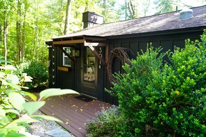 A cabin with a wooden deck, a door, and a chimney. - Peaceful Family Friendly Private Lake Waterfront Home Close to Skiing and Hiking (Bennington)