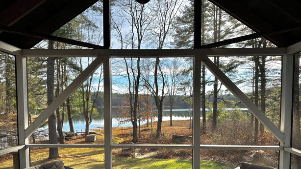 A conservatory with a view of a lake surrounded by trees. Inside, there are two sofas facing the glass walls. - Peaceful Family Friendly Private Lake Waterfront Home Close to Beach and Hiking (Bennington)