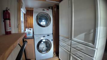 Cocina pequeña con lavadora y secadora, armarios de madera y extintor.