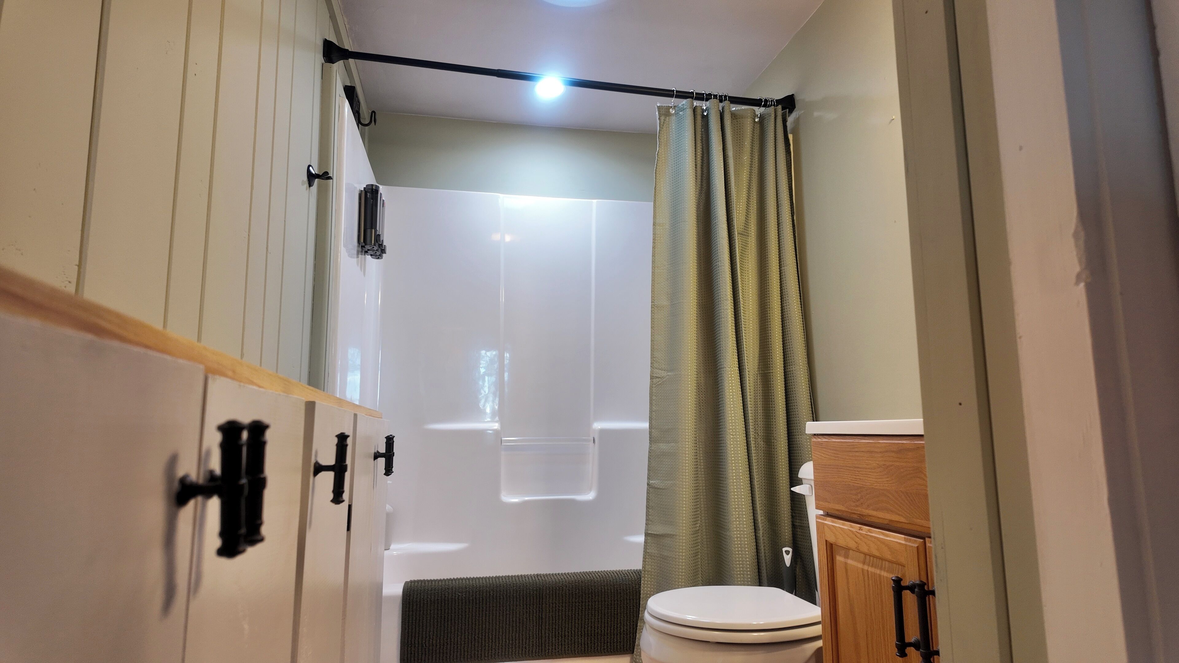 Une petite salle de bain avec douche, toilettes et meubles en bois.