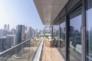 A high-rise balcony with a city view, featuring a wooden bench, a small table, and potted plants. - Stayshort - Lovely 3 Bed in Downtown Sleeps 5 With Balcony (Dubai)