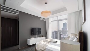 A modern hotel room with a large window, a bed, a bedside table, a TV, and a wardrobe. - Stayshort - Lovely 3 Bed in Downtown Sleeps 5 With Balcony (Dubai)