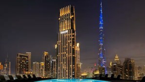 A rooftop pool with a city skyline in the background, including a prominent building with vertical lights and a tall tower with a spiral design. - Stayshort - Lovely 3 Bed in Downtown Sleeps 5 With Balcony (Dubai)