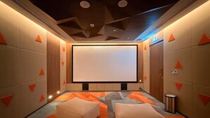 A modern home theater room with a large screen, comfortable seating, and a geometric ceiling design. - Stayshort - Lovely 3 Bed in Downtown Sleeps 5 With Balcony (Dubai)