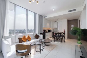 A modern living room with a sofa, coffee table, and dining area. - Stayshort - 1 Bed Unit in Meydan Sleeps 2 With Balcony (Dubai)