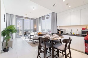 A modern apartment with a dining area, kitchen, and a balcony with a city view. - Stayshort - 1 Bed Unit in Meydan Sleeps 2 With Balcony (Dubai)