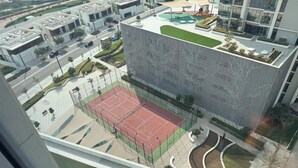 A modern building with a rooftop garden, a tennis court, and a landscaped courtyard. - Stayshort - 1 Bed Unit in Meydan Sleeps 2 With Balcony (Dubai)