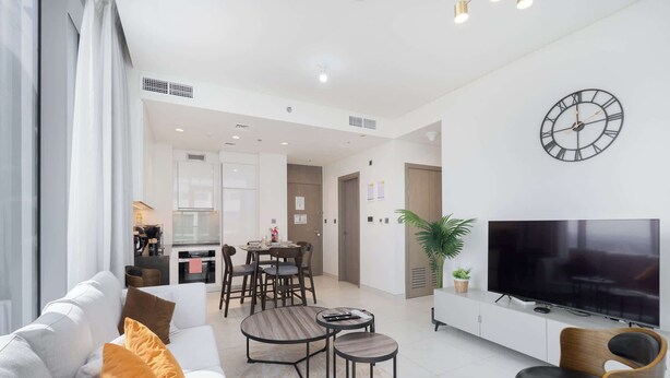 A modern living room with a sofa, coffee table, TV, and dining area. - Stayshort - 1 Bed Unit in Meydan Sleeps 2 With Balcony (Dubai)
