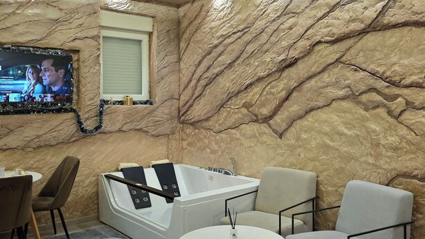 Une salle de bain moderne avec un mur en marbre, une baignoire et un téléviseur à écran plat fixé au mur.