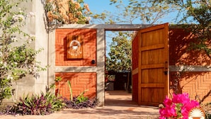 A wooden gate leading to a courtyard with a brick wall and a circular logo. - 4 Beds. Villa, Pool, Oceanview (Puerto Ángel)