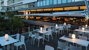 A modern building with multiple floors, large windows, and an outdoor seating area with tables and chairs. - Hotel Privo (Târgu Mureș)