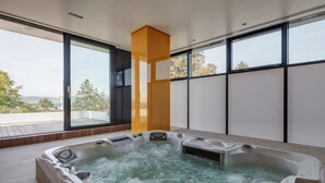 A modern spa area with a hot tub and a large window providing a view of the outdoors. - Hotel Privo (Târgu Mureș)