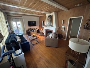 Ein Wohnzimmer mit einer Couch, einem Couchtisch, einem Kamin, einem Fernseher und einem großen Gemälde an der Wand.
