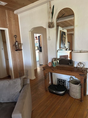 Ein Wohnzimmer mit Holzboden, einer Couch, einem Tisch mit Dekoration und einem Spiegel.