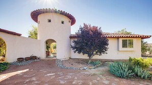 Una casa amb revestiment de calç, una torre, un porxo cobert i un petit arbre.