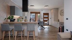 Eine moderne Küche mit Kochinsel, Barhocker und Essbereich mit Tisch und Stühlen.