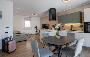 A modern kitchen with a dining area, a sofa, and a TV. There are suitcases and a plant in the room. - Beautiful home in Vodnjan with WiFi (Vodnjan)