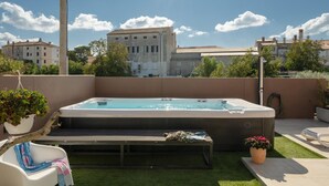 Eine Dachterrasse mit Whirlpool, einer Bank und Topfpflanzen.