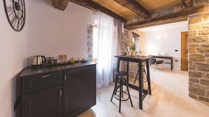 Una cocina rústica con techo de madera, paredes de piedra y una barra negra.