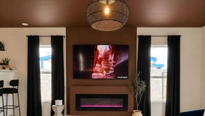 Una sala de estar moderna con un televisor de pantalla plana, una chimenea, una mesa de centro y un sofá.