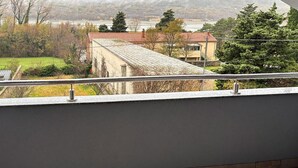 Uma varanda com vista para um edifício com telhado de telhas vermelhas e parede de pedra.