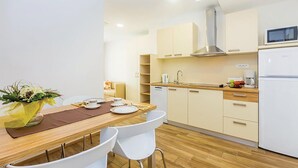 Eine moderne Küche mit weißen Schränken, einer Holz Arbeitsplatte und einer eingebauten Mikrowelle.