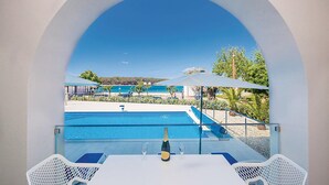 Vista de la piscina bajo un cielo azul despejado, con una mesa, una botella y vasos.