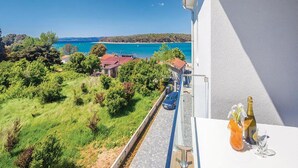 En balkong med fri utsikt över ett kustlandskap, inklusive en vattenyta och grönområden.