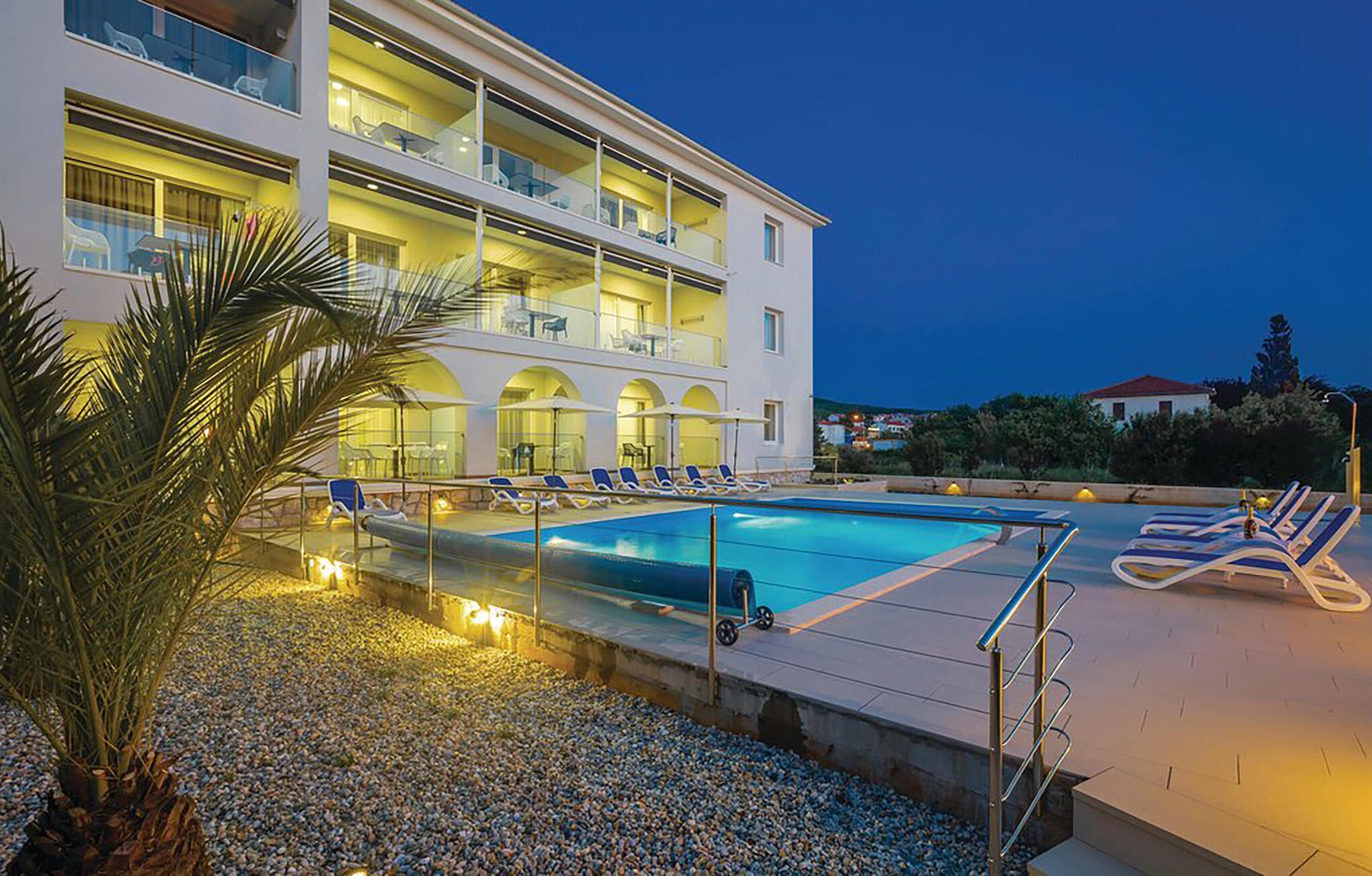 Un hôtel doté d’une piscine, de plusieurs balcons et d’un espace extérieur aménagé pour s’asseoir.