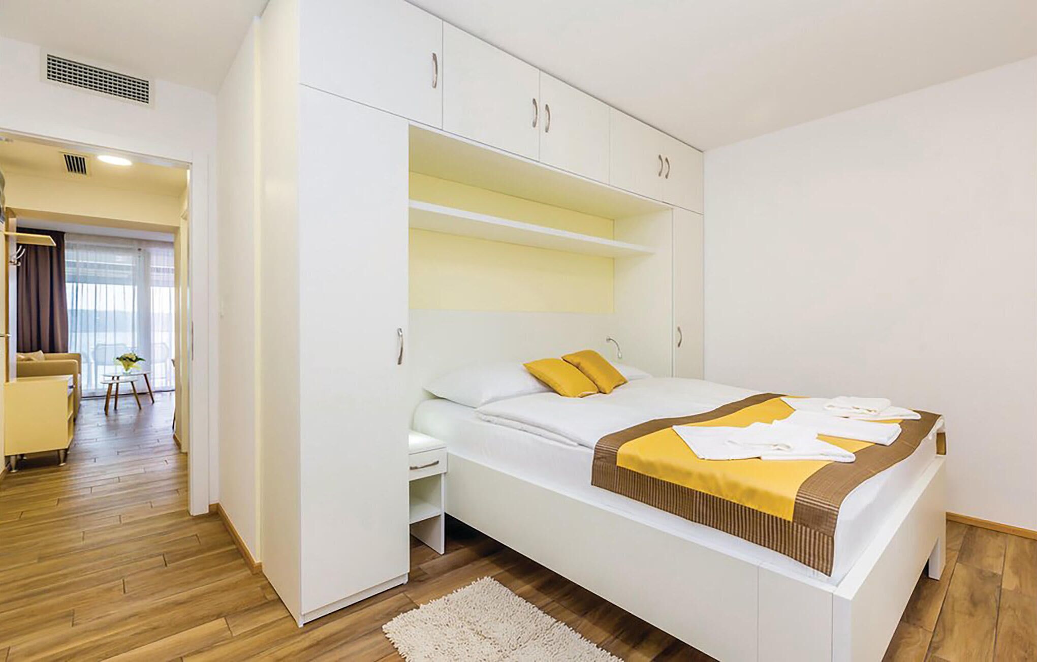 Una camera da letto con un letto, un armadio e una piccola zona salotto con tavolo e sedie.