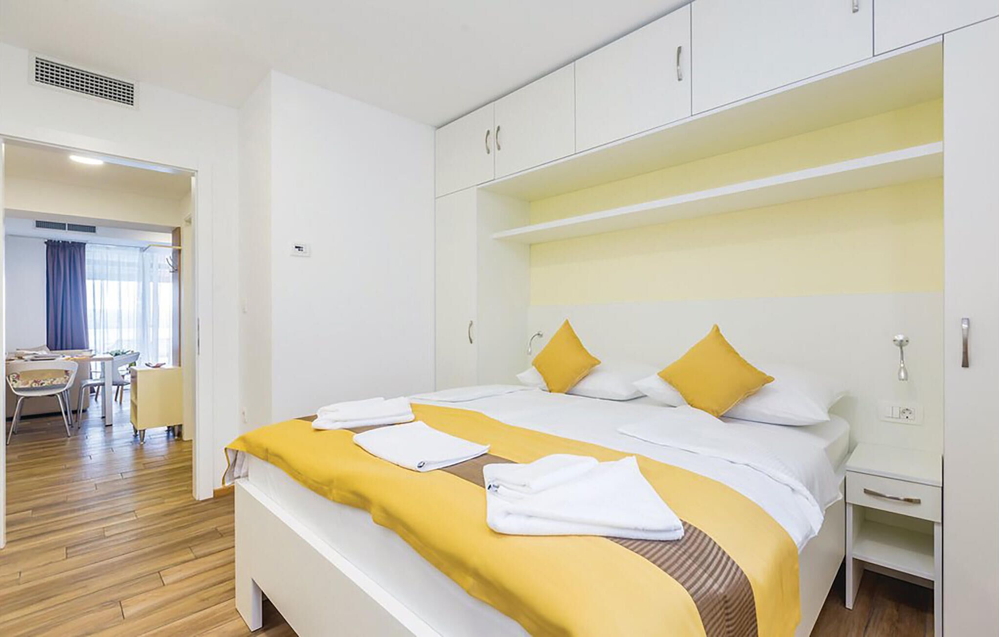A hotel room with a large bed, a bedside table, a wardrobe, and a desk with chairs.
