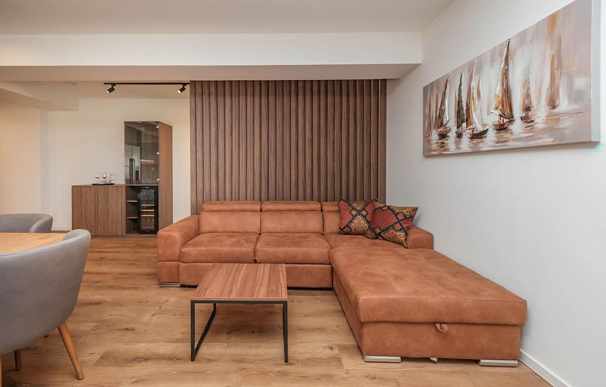 A modern living room with a sectional sofa, a small wooden coffee table, and a dining area with a grey chair.