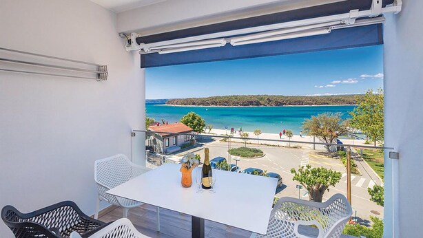 Varanda com mesa e cadeiras, com vista para a costa e céu limpo.