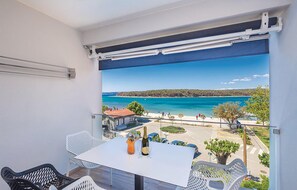 A balcony with a table and chairs, overlooking a coastal view with a clear sky. - 2 bedroom cozy apartment in Punat (Punat)