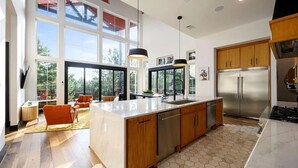 Una cocina moderna con una isla grande, electrodomésticos de acero inoxidable y ventanas amplias con vistas al exterior.