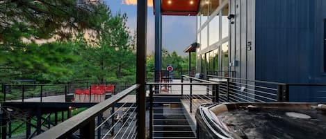A deck with outdoor seating, a hot tub, and a view of a forested area.