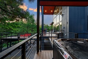 Een terras met buitenmeubilair, een hottub en uitzicht op een bebost gebied.
