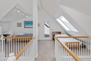 A bedroom with a sloped ceiling, a bed, a desk, and a chair.