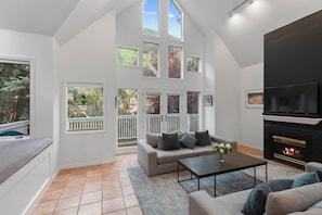 A spacious living room with a high ceiling, a fireplace, a sofa, and a coffee table. - 445 Depot Avenue – Elevated Telluride Comfort (Telluride)