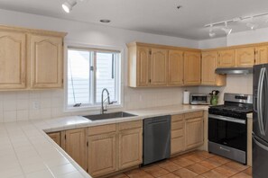 A kitchen with wooden cabinets, a stainless steel refrigerator, a dishwasher, and a stove.