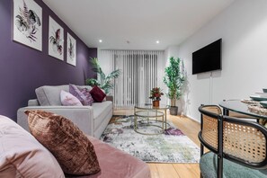 Ein modernes Wohnzimmer mit einer Couch, einem Couchtisch und einem an der Wand befestigten Fernseher.