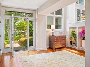 A room with a wooden floor, a large window, a dresser, and a potted plant. - MyStay at 35 Ruddy Turnstone - 5BR Oceanfront Luxury Living! (Hilton Head Island)