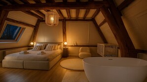 A bedroom with a large bed, bedside tables, a round bathtub, and a window with a view.