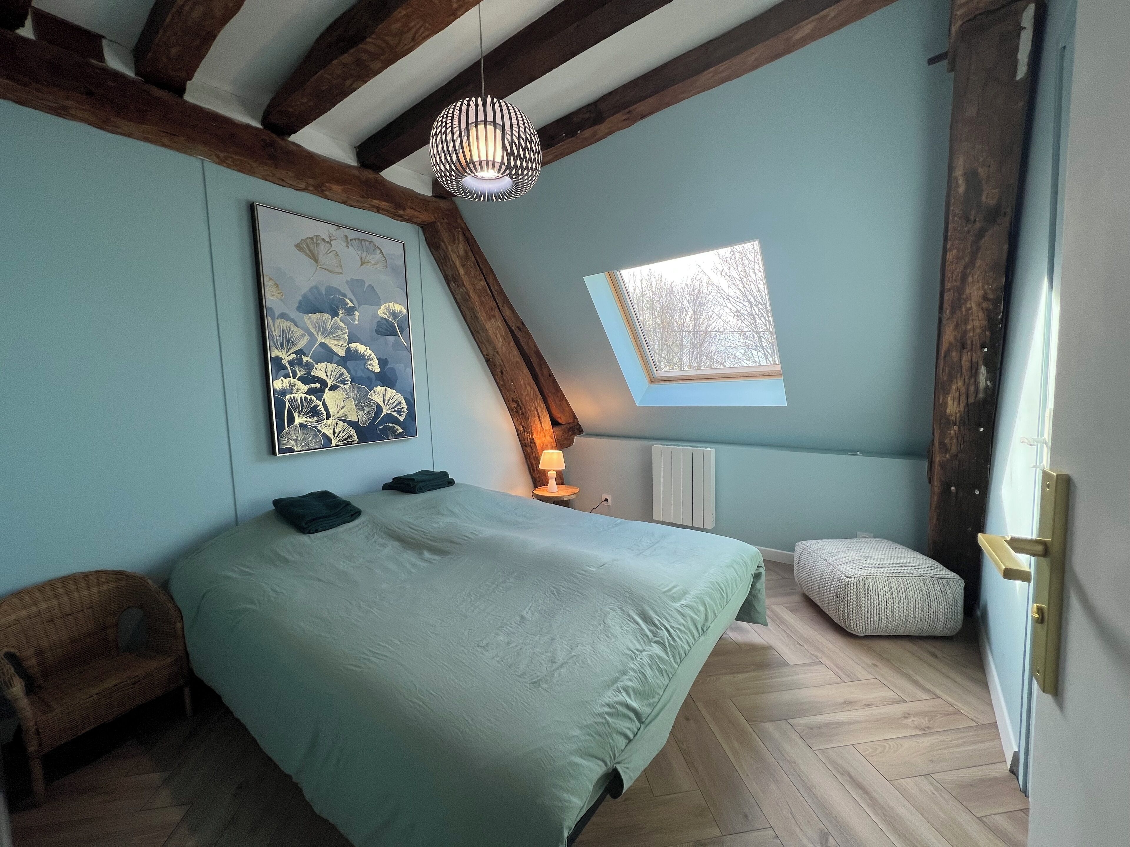 Une chambre à coucher avec un grand lit, une fenêtre, un radiateur et un luminaire suspendu.