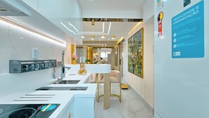 A modern kitchen with built-in appliances, a white countertop, and a dining area with a table and chairs. - Sofistica o na Gra a Calmaria a 5 min da Barra (Salvador)