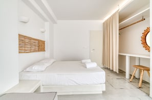 A minimalist bedroom with a bed, bedside tables, a wooden headboard, a mirror, and a door. - Spacious modern sea view apartment: AC, walk to taverns and beaches (Aliki)