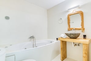 A modern bathroom with a freestanding bathtub, a wooden vanity with a bowl sink, and a mirror with a wooden frame. - Spacious modern sea view apartment: AC, walk to taverns and beaches (Aliki)