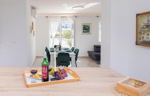 Ein stilvoller Essbereich mit einem Holztisch, der für eine Mahlzeit gedeckt ist, einer Weinflasche und einer Obstschale.