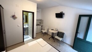 Een compacte kamer met een kitchenette, een eethoekje en een badkamer.